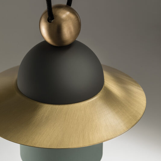 A close-up of the Contemporary Triple LED Pendant Light showcasing its matte black dome and flat, wide brass-colored ring. The slightly reflective brass ring contrasts with the smooth-textured black dome, while the light is suspended by a black cord that connects to a brass sphere.