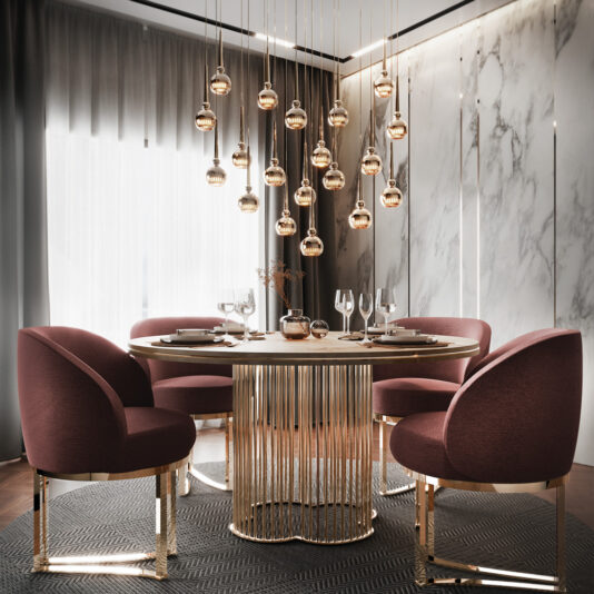 A modern dining room showcasing a round table with a gold base and glass top, paired with four plush maroon chairs with gold legs. Above the table, there's a stunning Large Modern Crystal Pendant Style Chandelier featuring suspended, round, gold lights. The room is adorned with marble accents and sheer curtains.