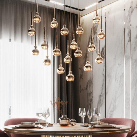 A contemporary dining room features a round wooden table set with four place settings and glassware. Above the table, a Large Modern Crystal Pendant Style Chandelier hangs from the ceiling. The backdrop includes floor-to-ceiling curtains and a marble accent wall.