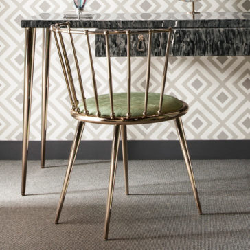 A modern dining chair with a gold metal frame and green cushioned seat is placed by a granite-topped bar or counter. Nearby, the 