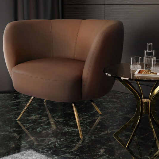 A modern interior showcases a plush, brown, curved-back armchair with gold legs. Beside it, a sleek, round table in black and gold holds a glass decanter and two glasses. The elegant setting is enhanced by a dark, marble-patterned floor and dark curtains in the background that complement the Modern Leather Tub Armchair perfectly.