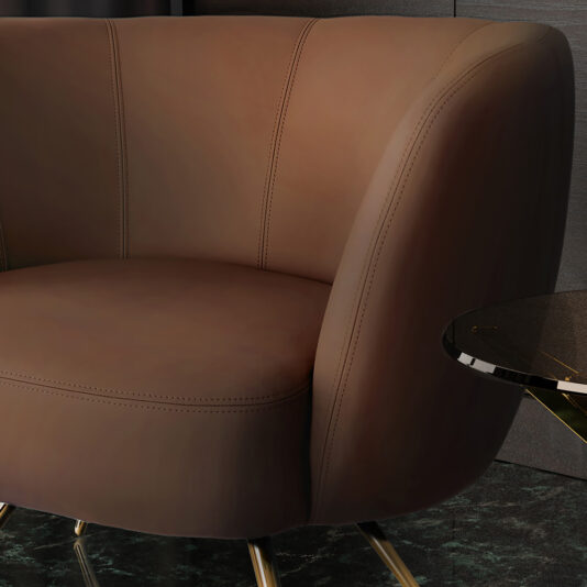 A close-up view of the Modern Leather Tub Armchair showcases its sleek, curved lines and gold legs. The armchair is complemented by a small, round glass side table with a gold base, set against a dark-toned background.