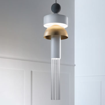 Modern LED Pendant Light A Modern LED Pendant Light with a sleek, minimalist design hangs from the ceiling. It features a two-tone shade with a metallic gold dome and a white cylindrical piece below it, from which thin metal rods extend downward in a fringe-like pattern. The background is a plain, light-colored wall.