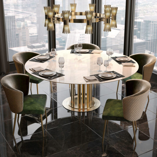 A luxurious dining setup featuring the Round Marble Dining Table And Chairs Set, which includes a round marble table with a sophisticated gold base, surrounded by five exquisite green velvet chairs. The table is perfectly set with glasses, plates, and napkins. An elegant chandelier hangs above, while large windows provide a stunning panoramic view of the cityscape in the background.