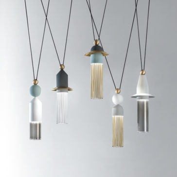 The Set Of Modern Pendant Lights boasts unique designs, incorporating gold, silver, and white elements along with decorative fringe-like accents. Hanging from black cords against a plain, light-colored background, this set of five lights brings a contemporary flair to any space.