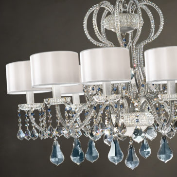 Traditional Italian Crystal Chandelier A close-up view of the Traditional Italian Crystal Chandelier reveals intricately designed crystal-adorned arms and large teardrop-shaped prisms. It features multiple white fabric lampshades and exquisite detailing, with the crystals reflecting light to create a mesmerizing sparkling effect.
