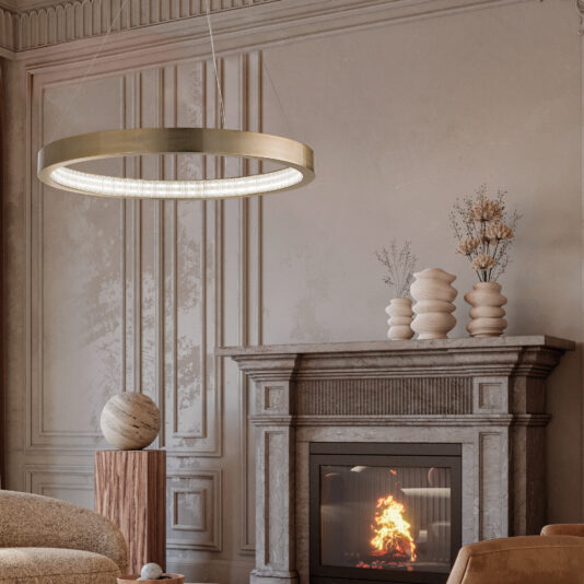 A Contemporary Round Chandelier graces the living room ceiling, while a stone fireplace flickers below, decorated with vases and decor on its mantel. Intricate wall moldings complement a round sculpture on a wooden pedestal.