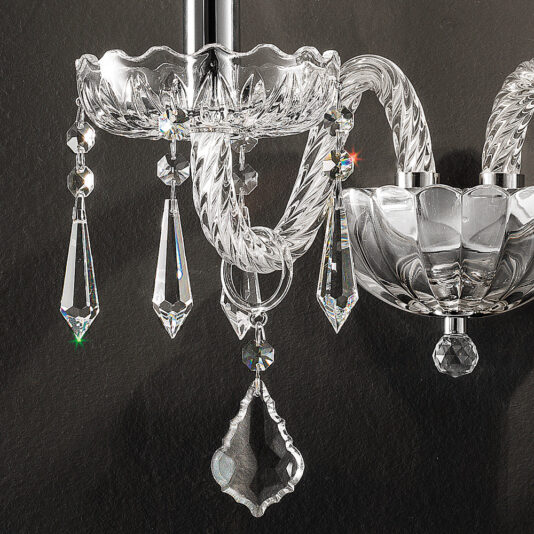 Contemporary Crystal Pendant Wall Light Close-up of a Contemporary Crystal Pendant Wall Light showcasing its intricate detailing. The design features twisted glass arms and hanging crystal pendants that catch light, creating sparkling reflections. The dark background highlights the brilliance of the crystals, enhancing its contemporary elegance.