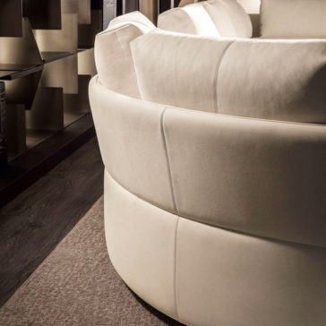 A close-up of the Contemporary Leather Modular Corner Sofa in a modern cream color, featuring oversized cushions. The sofa boasts a smooth texture and is placed next to a dark, patterned wall and wooden floor, creating a stylish, contemporary living space.