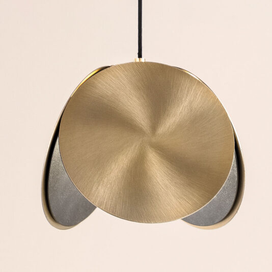 Contemporary Metal Disc Pendant Light The Contemporary Metal Disc Pendant Light boasts a sophisticated design with a circular, brushed brass shade and a black cord at the top. Its minimalistic aesthetic makes it an elegant addition to any contemporary interior decor.