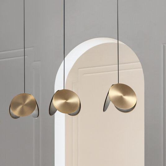 Contemporary Metal Disc Pendant Light A modern minimalist interior showcases three Contemporary Metal Disc Pendant Lights adorning the space in front of an arched doorway. These pendant lights boast a sleek and stylish design, casting a warm, ambient glow against the neutral-toned walls and smooth textures.