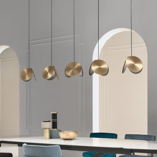 A modern dining room with a minimalist design featuring an arched doorway and the Contemporary Metal Disc Pendant Light, which showcases five gold, disc-shaped lights. The space is decorated in neutral tones, complemented by a white dining table and blue chairs.