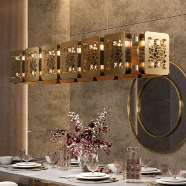 A modern dining room features a Contemporary Rectangular Chandelier with intricate gold detailing hanging above a set table. The table is adorned with elegant place settings, crystal glasses, and a centerpiece of dried flowers in a glass vase. A round mirror hangs on the wall.
