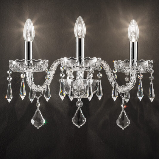 The Contemporary Silver Crystal Pendant Wall Light mounted on a dark wall. The sconce features three candle-shaped bulbs, ornate crystal arms, and intricate hanging crystal pendants reflecting the light, creating a luxurious and elegant appearance.
