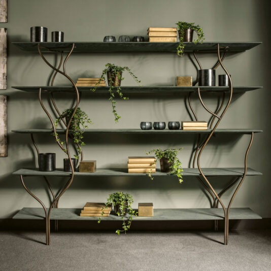 The Contemporary Wrought Iron Bookcase exudes style with its organic design elements, showcasing multiple shelves supported by intricate, winding metal supports. Perfect for holding books, potted plants, and decorative black and gold objects, this chic shelving unit stands prominently against a green wall on a gray carpet.