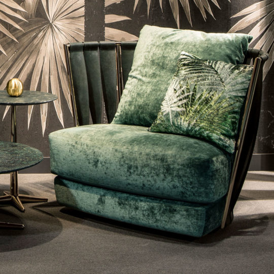 An exclusive modern leather twist on the classic design, our plush green Exclusive Modern Leather Twist Armchair comes with a matching leafy throw pillow and sits beside two round side tables. The dark wallpaper backdrop adorned with abstract leaf designs completes this sophisticated look.