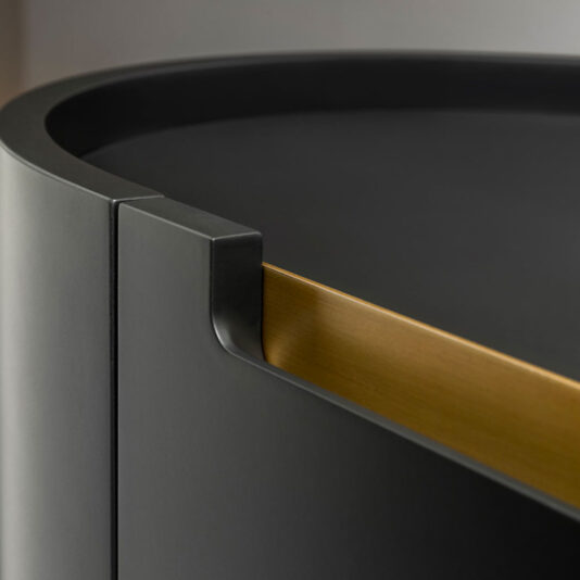 A close-up image of the Large Modern Curved Cabinet, featuring its rounded edge and contrasting gold interior accent. The design showcases a minimalist aesthetic with smooth surfaces and precise lines, highlighting the cabinet's sleek and contemporary appeal.