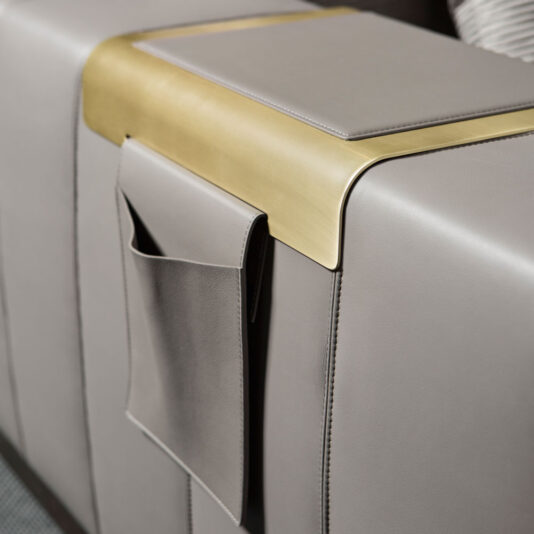 Luxurious Contemporary Modular Corner Sofa Close-up of the armrest of the Luxurious Contemporary Modular Corner Sofa, showcasing its sleek grey leather upholstery, built-in brass tray, and convenient side storage pocket. The modern design is characterized by its clean lines and high-quality materials.