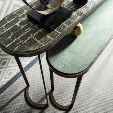 Modern Console Table Set A top-down view of the Modern Console Table Set reveals two chic nesting tables; one showcases a green marble-like surface while the other is adorned with a green velvet-like texture. They are set on a grey-patterned rug with geometric wallpaper in the background, and decor items elegantly embellish the top table.