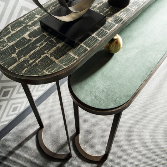Modern Console Table Set A top-down view of the Modern Console Table Set reveals two chic nesting tables; one showcases a green marble-like surface while the other is adorned with a green velvet-like texture. They are set on a grey-patterned rug with geometric wallpaper in the background, and decor items elegantly embellish the top table.