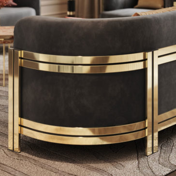 A close-up of the Modern Curved Sofa With Brass Frame, featuring dark, plush fabric upholstery and shiny, golden metal legs. The metallic gold accents add a touch of sophistication to the design. The background shows a textured carpet.