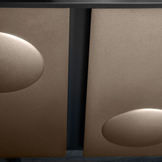 Modern Industrial 4 Door Sideboard A close-up image of the Modern Industrial 4 Door Sideboard showcases its sleek, contemporary design with a matte dark finish. The door surfaces feature two prominently placed circular indents, symmetrically enhancing its minimalist and modern aesthetic.