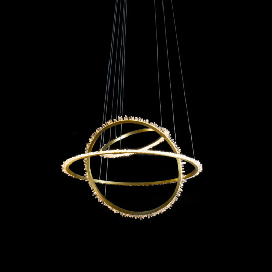 The Modern Quartz Crystal Hoop Chandelier, featuring three intertwined, illuminated rings, hangs against a black background. The rings are adorned with small decorative elements that add texture and shine.