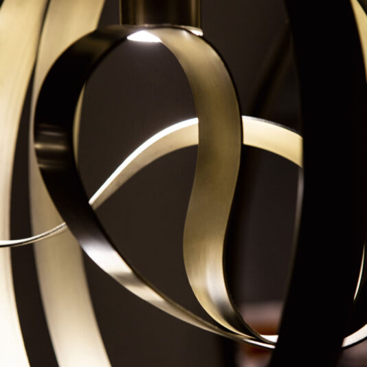 Modern Twisted Bronze Chandelier Close-up of the Modern Twisted Bronze Chandelier, showcasing intertwined metallic ribbons and glowing lights. The curving, smooth lines create a dynamic and artistic effect against a dark background.
