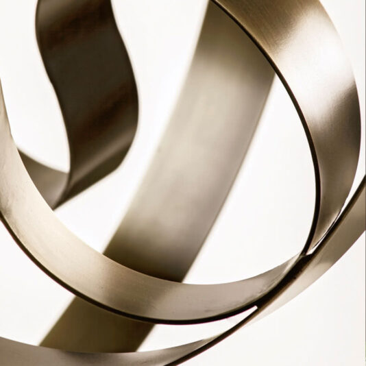 Modern Twisted Bronze Chandelier A close-up view of the Modern Twisted Bronze Chandelier reveals an abstract metal sculpture with smooth, curved, and intertwined metallic strips. The surface of these strips has a reflective, brushed finish, giving the chandelier a contemporary and dynamic appearance against a plain background.