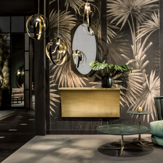 Modern Twisted Bronze Chandelier A chic modern interior showcases a tropical-themed wallpaper adorned with large leaf patterns, complemented by a golden console table and an oval mirror with a black frame. Elegant gold hanging light fixtures and a green marble coffee table enhance the luxurious feel, further accentuated by the exquisite Modern Twisted Bronze Chandelier.