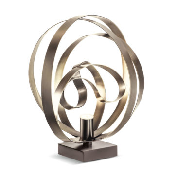 Modern Twisted Bronze Table Lamp The Modern Twisted Bronze Table Lamp showcases intertwined metallic ribbons sculpted into a circular design, all mounted on a square base. Its light source is centrally positioned at the bottom, casting a warm glow that beautifully highlights the twisted ribbons.