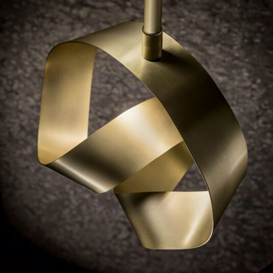 The Modern Twisted Bronze Wall Light boasts an intertwined, bronze ribbon-like design set against a dark textured backdrop. This sleek and artistic light fixture effortlessly adds an elegant touch to any environment.