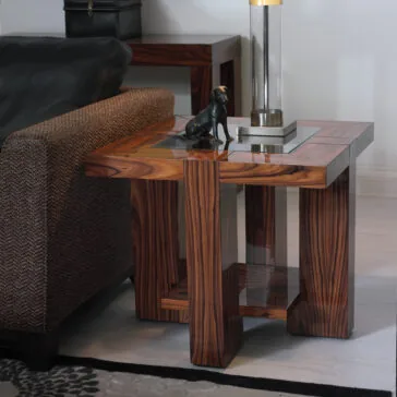 Contemporary Square End Table With Glass Top A modern living room features a Contemporary Square End Table With Glass Top beside a cushioned armchair. The table holds a sleek black statue and a contemporary lamp with a transparent base, all set on a light-colored floor and patterned rug.
