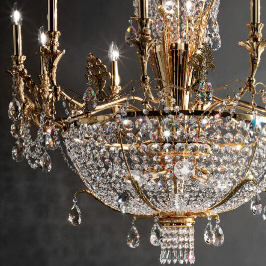 A close-up of the Classic Gold Plated Crystal Empire Chandelier reveals its intricate gold detailing and numerous sparkling crystal elements. The gold-plated chandelier is illuminated, featuring several small bulbous lights and an array of hanging crystal ornaments that beautifully reflect the light.