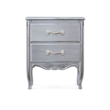 Classic Ornate Bedside Cabinet The Classic Ornate Bedside Cabinet is a vintage-style silver nightstand with two drawers, each adorned with intricate white floral handles. The cabinet stands on four elegantly curved legs and features ornate carvings on the drawer fronts and bottom panel against a solid white background.