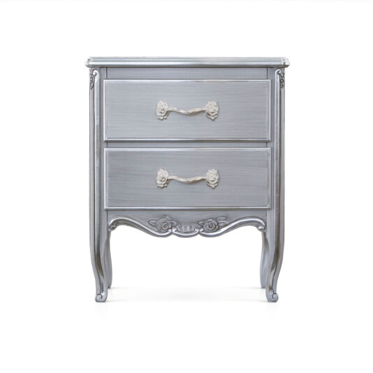 The Classic Ornate Bedside Cabinet is a vintage-style silver nightstand with two drawers, each adorned with intricate white floral handles. The cabinet stands on four elegantly curved legs and features ornate carvings on the drawer fronts and bottom panel against a solid white background.