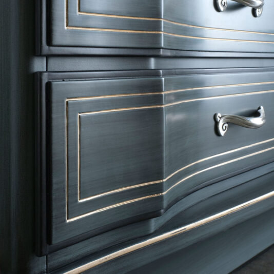 Close-up of the Classic Style Italian Chest Of Drawers in dark blue, showcasing a distressed finish with silver handles and gold detailing on the edges. The ornate, vintage-inspired design emphasizes the craftsmanship and elegance characteristic of traditional Italian furniture.