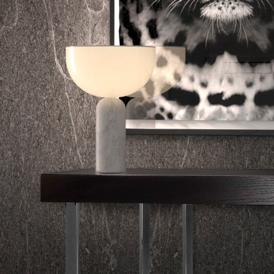 A sleek table lamp with a marble base and a semi-circular white shade is placed on the **Modern Black Console Table With Drawer**. The background showcases a textured grey wall adorned with a black-and-white abstract art piece featuring an animalistic design.