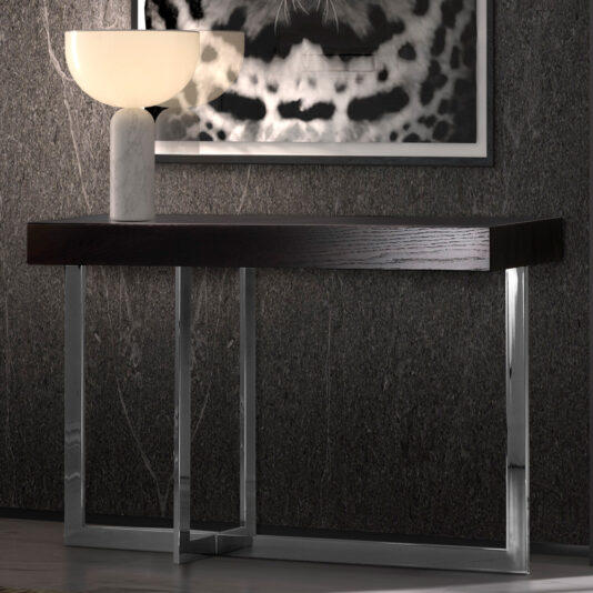 The Modern Black Console Table With Drawer, featuring sleek metal legs, stands against a textured, dark gray wall. A white lamp with a marble base and a wide, shallow shade is placed on the table. Above the table hangs an abstract black and white artwork.