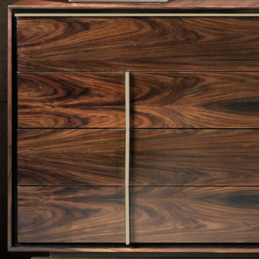 Contemporary Elegant Double Dresser The Contemporary Elegant Double Dresser is crafted from wood and features six drawers with a rich, dark brown wood grain. Two vertical metal handles are centered, accentuating the natural patterns and swirls in the wood. The cabinet corners boast a slightly worn, dark metal frame for an added touch of elegance.