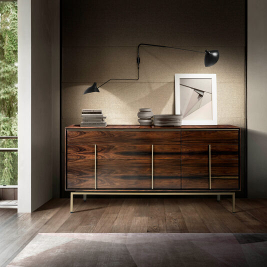 Contemporary Elegant Double Dresser A contemporary wooden Contemporary Elegant Double Dresser with a sleek, minimalist design stands against a light-colored textured wall. On top of the elegant double dresser are books and a framed photograph. A black reading lamp with an adjustable arm is mounted on the wall above. A large window is visible to the left.