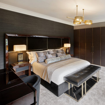 Contemporary Leather Bench A luxurious bedroom showcasing a large bed with a padded headboard, adorned with decorative pillows and a bolster. Nightstands with lamps are placed on either side, while modern pendant lighting hangs overhead. At the foot of the bed stands the Contemporary Leather Bench, and a spacious wardrobe completes the room.