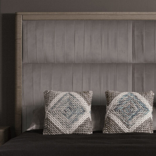 A neatly made bed showcases the Contemporary Oak Veneer Upholstered Bed, highlighted by its headboard with vertical stitching. Two decorative pillows featuring a textured diamond pattern in shades of grey and blue are symmetrically placed against the headboard. The dark-colored bedding enhances the minimalistic and cozy ambiance.