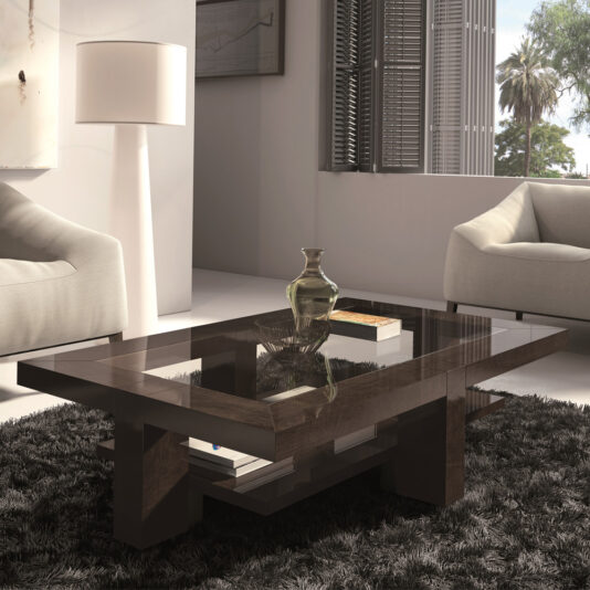 A modern living room featuring a Contemporary Rectangular Coffee Table With Glass Top and a wooden base, placed on a dark shaggy rug. The table holds a decorative vase and books. Two white armchairs flank the table, while a tall floor lamp stands in the background near a window with blinds.