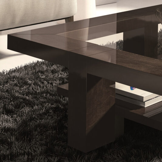 A contemporary rectangular coffee table with a glass top, featuring dark wood supports, is placed on a thick black shag rug. Part of a beige sofa can be seen in the background. Two books are neatly stacked on the lower shelf of the Contemporary Rectangular Coffee Table With Glass Top.