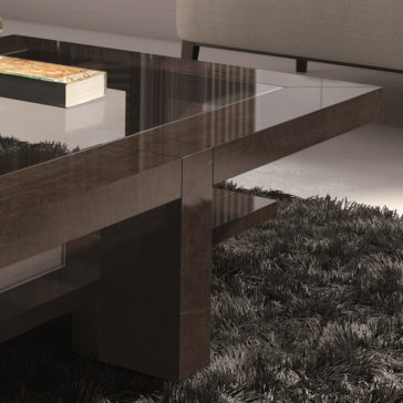 Contemporary Rectangular Coffee Table With Glass Top In a modern living room, the focal point is the Contemporary Rectangular Coffee Table With Glass Top, featuring dark wooden legs and a lower shelf where a book rests. The plush floor is covered with a dark shag rug, while part of a light-colored couch can be seen in the background.