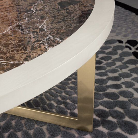 Contemporary Round Marble Top Coffee Table Close-up of a round coffee table with a brown marble top and a white edge. The table has a gold metal leg and is placed on a patterned rug with grey circular shapes.