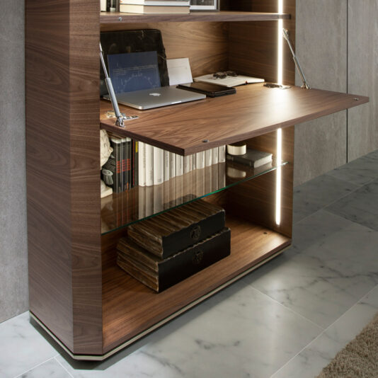 Contemporary Wooden Writing Desk The Contemporary Wooden Writing Desk features a sleek, modern design with a fold-out table surface. On top of the desk, you'll find a laptop, an assortment of books, and a notepad neatly arranged. Beneath the desk, shelves provide ample space for additional books and decorative storage boxes. LED lighting accents the interior, enhancing its stylish appeal.