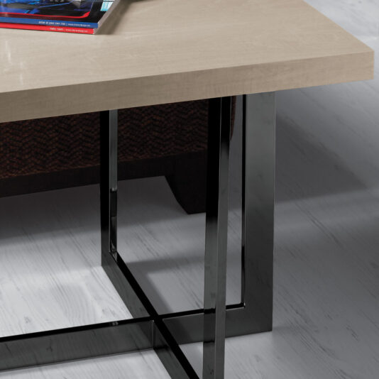 Contemporary Wooden End Table With Black Base A close-up of the Contemporary Wooden End Table With Black Base showcases its light-colored rectangular tabletop and sleek metal legs. On the table, a closed laptop and a couple of books are partially visible. The floor underneath is a light grey tone, contributing to the minimalist aesthetic.