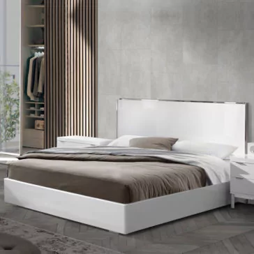 Deluxe Miami Style White Lacquered Bed A modern bedroom showcases a Deluxe Miami Style White Lacquered Bed adorned with gray and white bedding. Flanking the bed are a pair of white nightstands. The room highlights gray walls, wooden accents, and an open wardrobe displaying hanging clothes in the backdrop. Sunlight streams through a window, bathing the space in natural light.